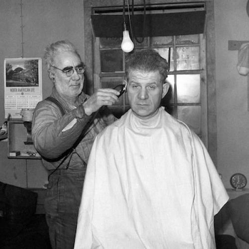 'Pop' the mechanic moonlights as a barber at the Discovery Mine bunkhouse, 1951. (Herman Nyland Collection)